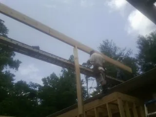 Carpenter setting a ridge beam over a new addition frame — Ice Dam Removal by Roofing Brothers in Letohatchee
