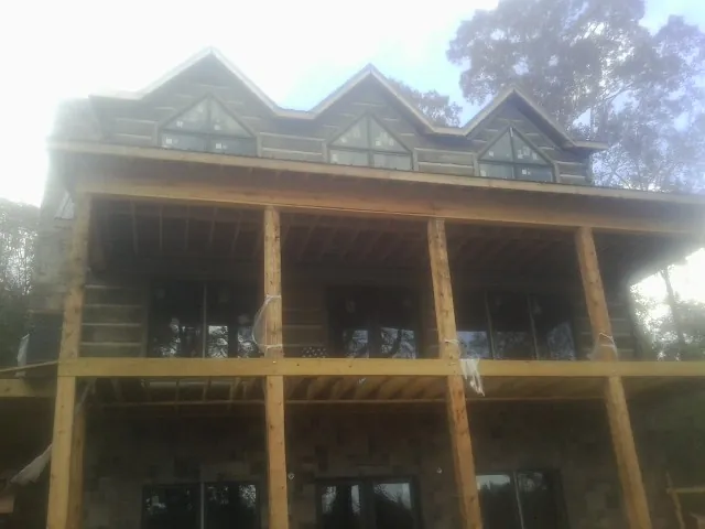 Dormers and porch framing on a large log home under construction — Roof Coating work by our crew in Letohatchee