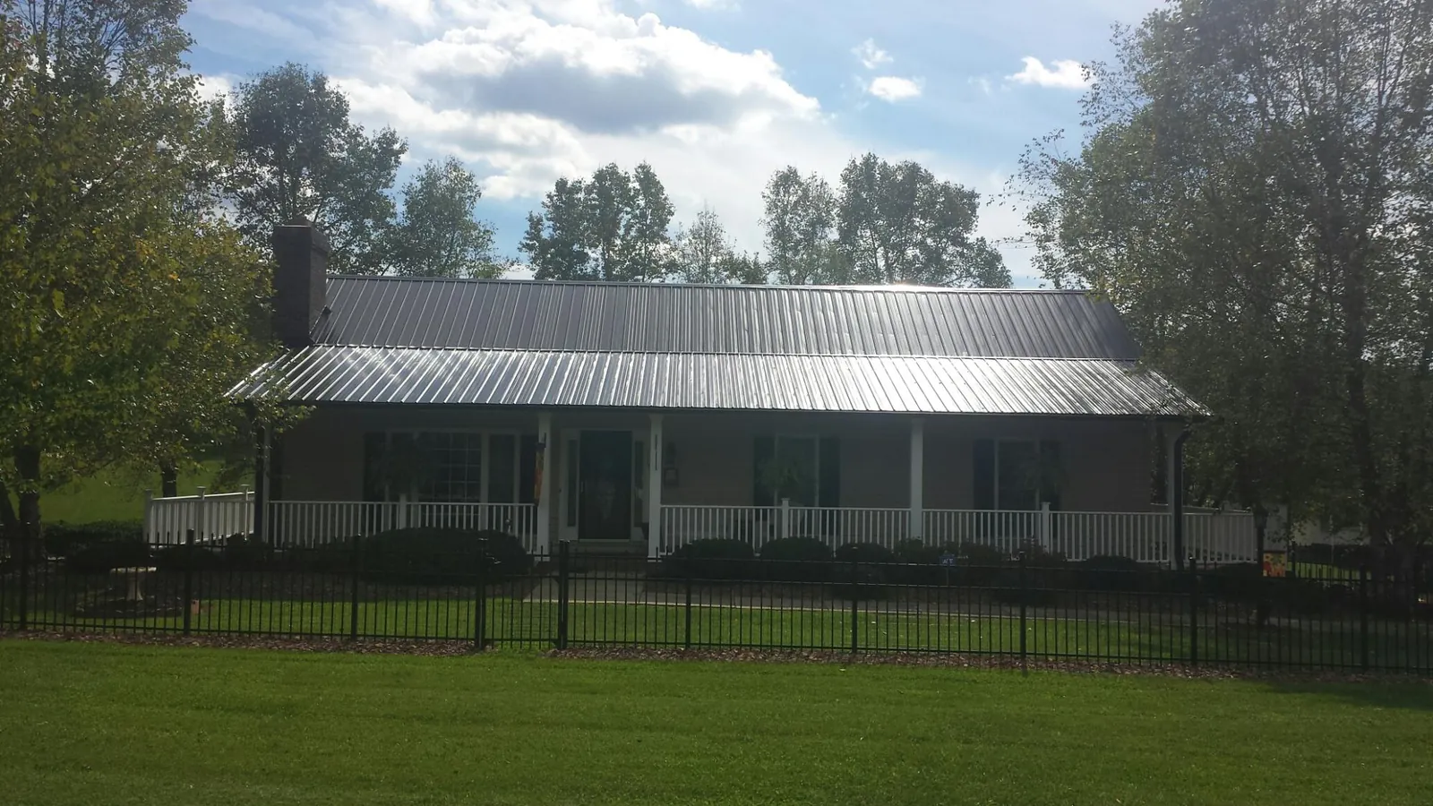 Gray metal roof on a brick ranch with a full width front porch — Gutter Guard Installation work by our crew in Letohatchee