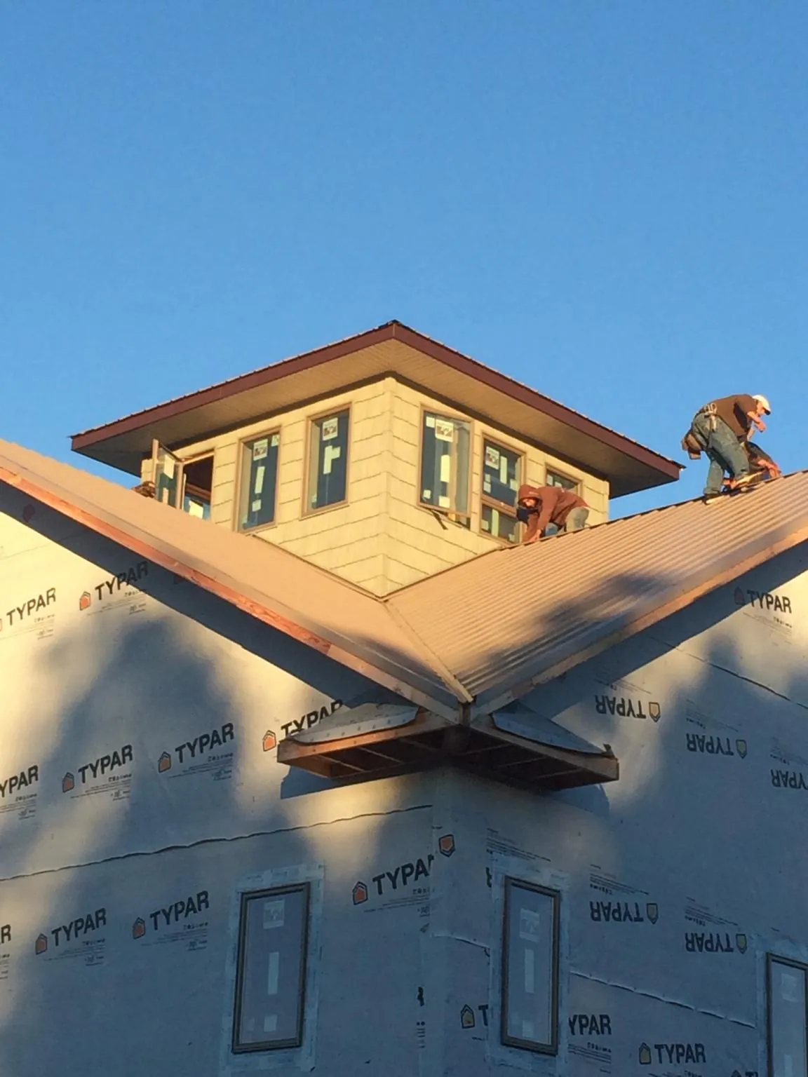 Roofers working around a rooftop cupola on a new metal roof at sunset — Roof Waterproofing in Letohatchee by Roofing Brothers